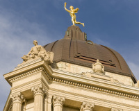A photo of the dome of the Manitoba Legislative Building in Winnipeg.  The dome is topped by Golden Boy, a gold-covered bronze statue sculpted by Georges Gardet.  Designed by Frank Worthington Simon and Henry Boddington III in a Classical Revival style, the Manitoba Legislative Building was completed in 1920.  This photo © Capitolshots Photography/TwoFiftyFour Photos, LLC, ALL RIGHTS RESERVED.